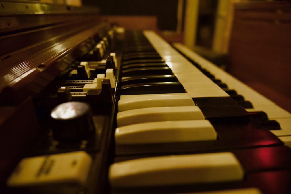 Close-up of a vintage Hammond B3 organ keyboard in low light, highlighting the contrast between white and black keys with a warm, nostalgic ambiance.